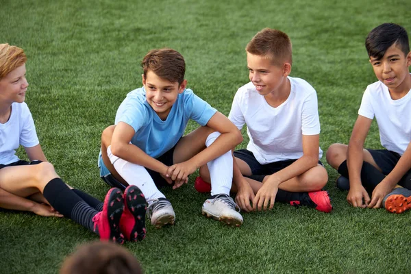 Grupo de meninos caucasianteen felizes em uniformes de futebol tendo um descanso no campo do esporte — Fotografia de Stock