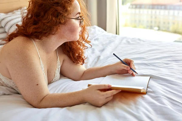 Soñadora pelirroja bonita mujer escribir poemas acostado en la cama —  Fotos de Stock