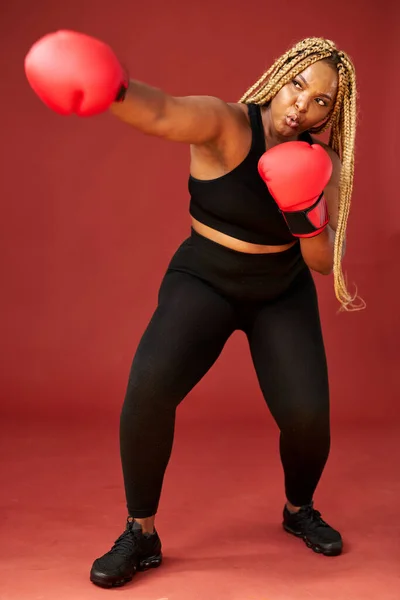 Atraktivní mladý tuk černošky sportovní fitness boxer žena ve sportovním oblečení pracuje izolované na červeném pozadí — Stock fotografie