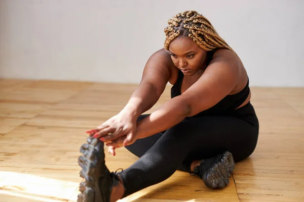 魅力的なプラスサイズアフリカ系アメリカ人女性が床にストレッチ — ストック写真