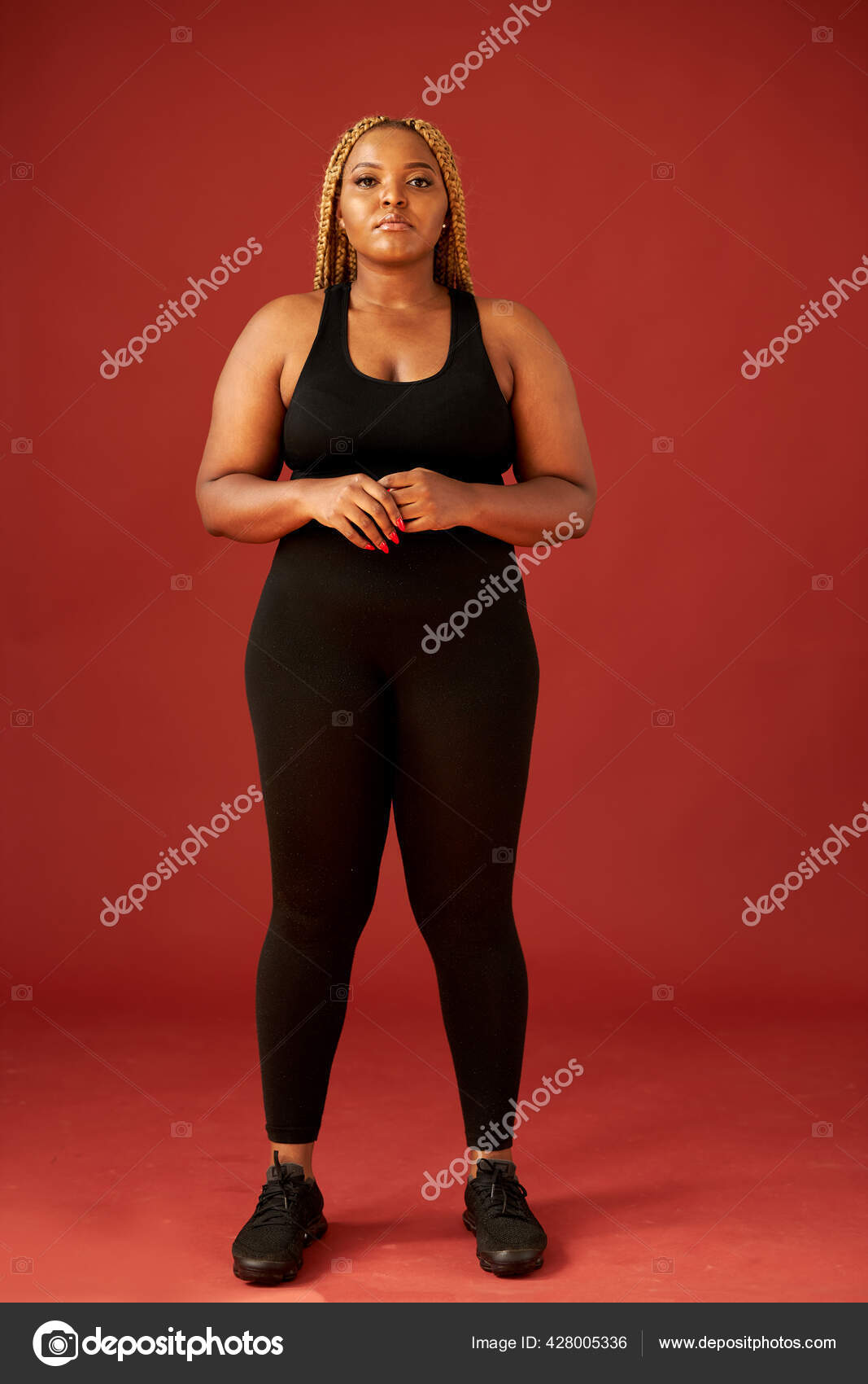 Confident fat african woman in black sportswear isolated on red background  Stock Photo by ©romanchazov27 428005336
