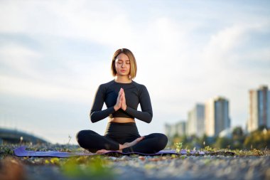 Kafkasyalı genç kadın, elleri bağlı bir paspasın üzerinde rahatça oturuyor.