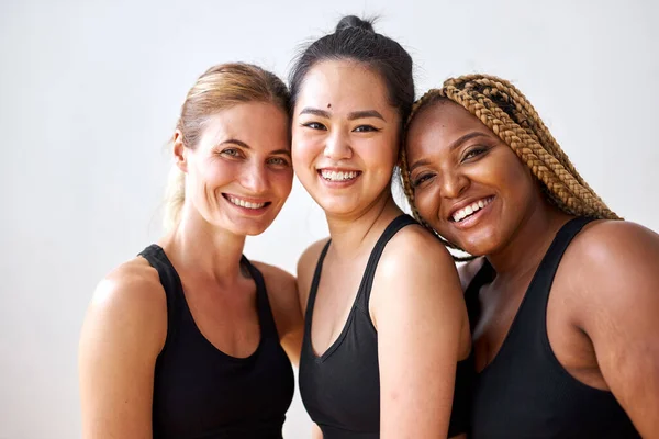 Έννοια φυσικής ομορφιάς. τρία διαφορετικά θηλυκά σε μαύρο αθλητικό ντύσιμο χαμογελώντας — Φωτογραφία Αρχείου