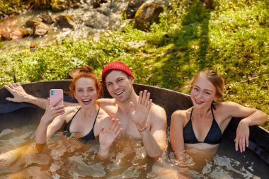 Gençler açık havada banyo yapıyor.