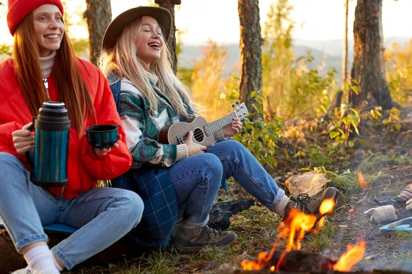 Giovani amici rilassarsi comodamente e bere tè caldo in una serata d'autunno all'aria aperta — Foto Stock