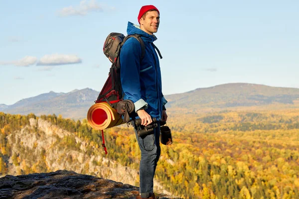 Standing young man with backpack on the mountain peak — Stock Photo, Image