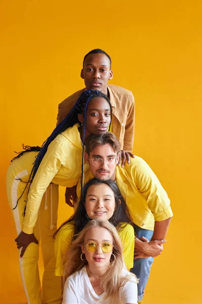 Groupe d'amis multiethniques, personnes de cultures différentes isolées sur fond jaune — Photo