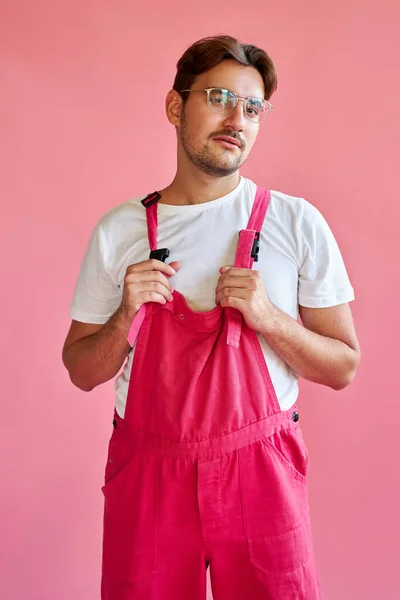 Portret van knappe blanke man in stijlvolle roze overall geïsoleerd — Stockfoto