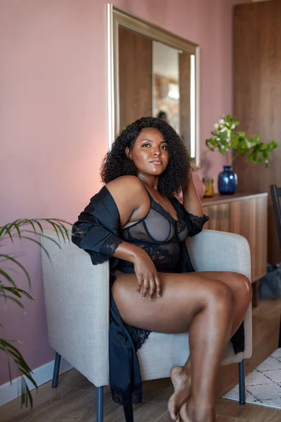 Mooi Afrikaans plus size model zit op stoel thuis, rust hebben — Stockfoto