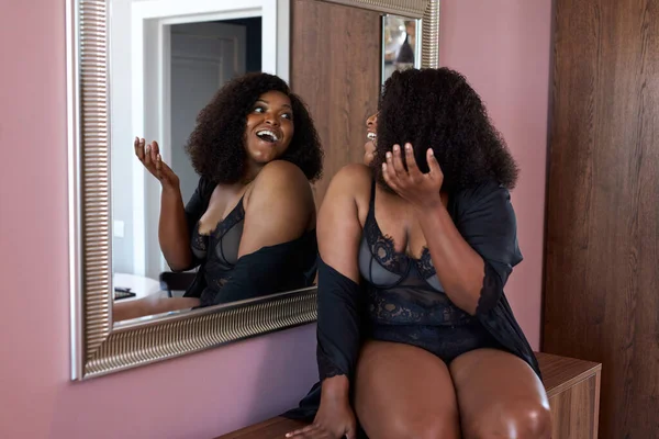 beautiful overweight african lady looks at mirror in living room