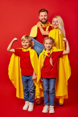 Parkta süper kahraman gibi davranan mutlu bir beyaz aile.