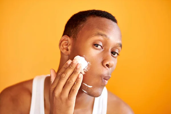 Guapo afroamericano hombre está aplicando espuma de afeitar antes de afeitarse cerda — Foto de Stock