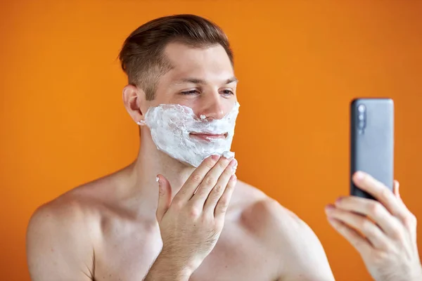 Agradable hombre está aplicando espuma de afeitar en la cara antes de afeitarse la cerda — Foto de Stock