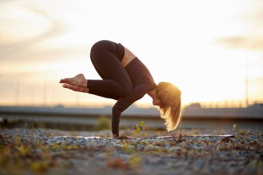 Kadının yandan görünüşü yoga dengeleyici asana - karga pozu veriyor