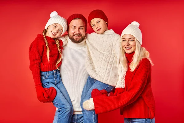 Familia joven caucásica en suéteres, aislada sobre fondo rojo de la pared —  Fotos de Stock
