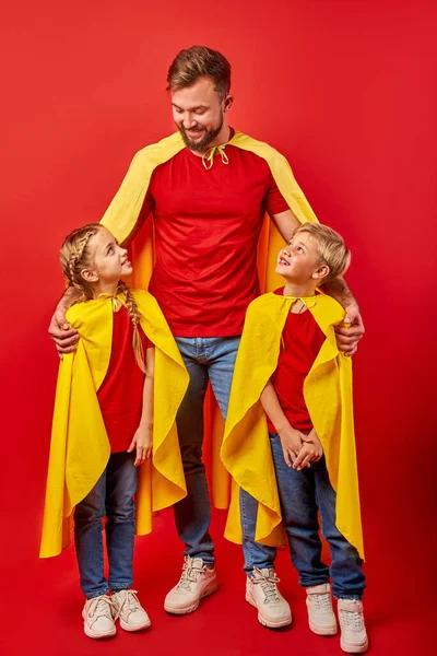 Super famille en manteaux debout isolé sur fond rouge — Photo