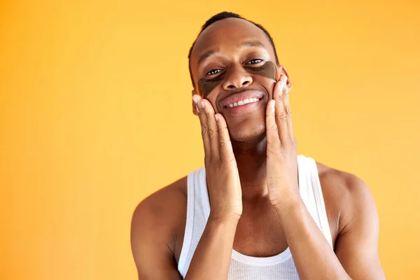 Retrato de homem americano africano sorridente com manchas de hidrogel preto sob os olhos — Fotografia de Stock