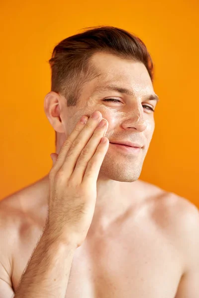 Hombre caucásico guapo cuida de su piel, la hidrata — Foto de Stock