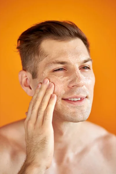 Jeune homme caucasien appliquer crème hydratante pour le visage pour une peau éclatante saine, isolé — Photo