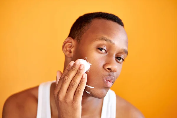 Siyah Afrikalı adam duştan sonra tıraş köpüğü sürer, güzellik ameliyatı yapar. — Stok fotoğraf