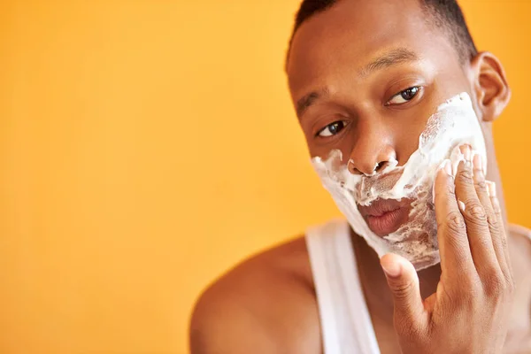 Homme noir avec mousse à raser sur son visage faisant la procédure de routine du matin — Photo