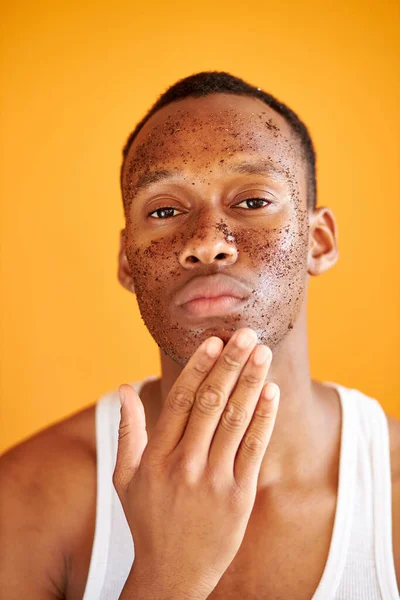 Afrikalı adam portakal rengi arka planda izole edilmiş yüz fırçası kullanıyor. — Stok fotoğraf