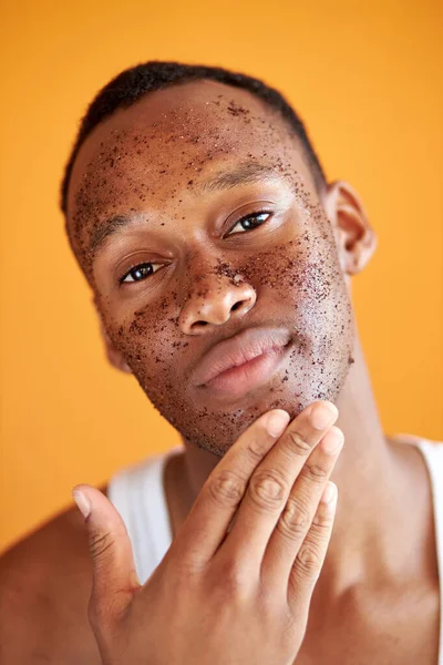 Fiatal afro-amerikai srác alkalmazása arc krém a szeme alatt sárga háttér — Stock Fotó