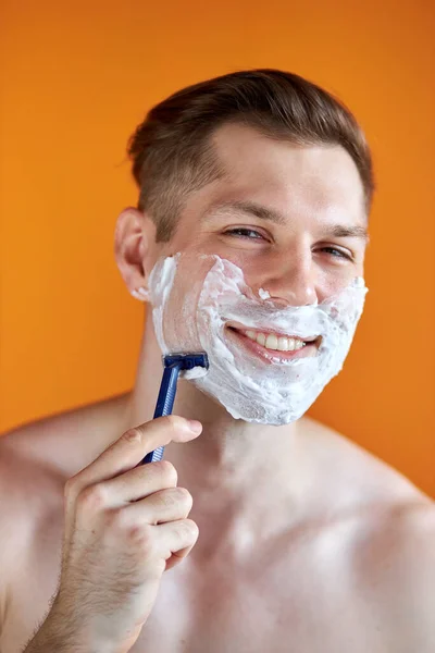 Hombre caucásico con espuma blanca en la cara, aislado sobre fondo naranja — Foto de Stock