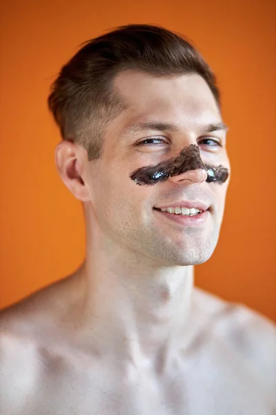 Καυκάσιος άνδρας με επίθεμα περιποίησης δέρματος στη μύτη, απομονωμένος σε πορτοκαλί φόντο — Φωτογραφία Αρχείου