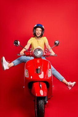 Mutlu, heyecanlı, kızıl saçlı kadın bacaklarını açmış motosiklet kullanıyor.
