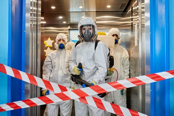 Équipe de désinfectants portant des combinaisons EPI pour se protéger contre le pulvérisateur COVID-19 — Photo