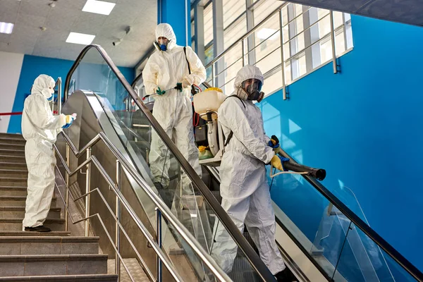 Desinfectante con trajes protectores desinfectando escaleras con productos químicos en aerosol — Foto de Stock