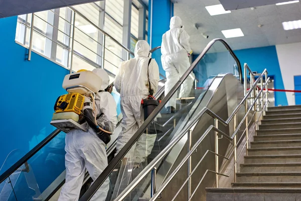 Equipo en trajes de protección contra virus van a limpiar desinfectar el edificio —  Fotos de Stock