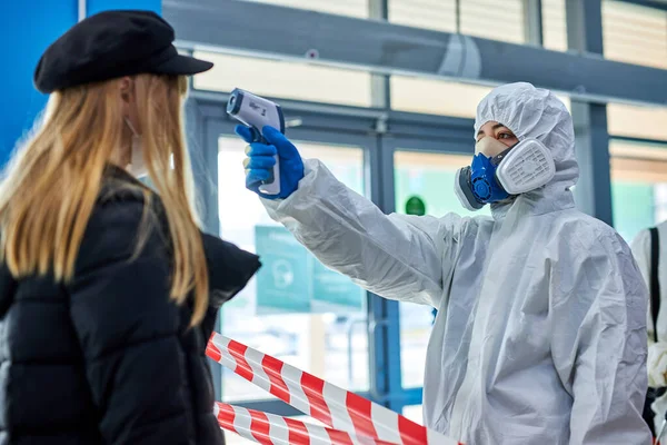 Fertőtlenítőszerek infravörös hőmérő berendezéssel ellenőrzik a homlok hőmérsékletét. — Stock Fotó