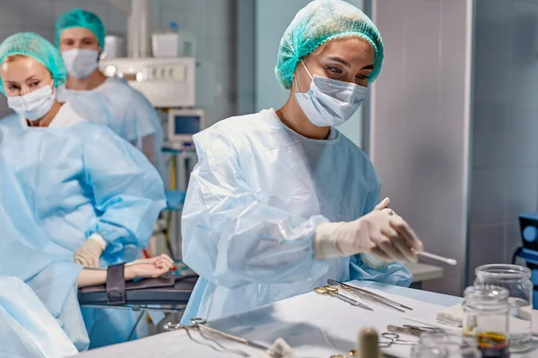 Assistant utile traite les instruments, fournit les instruments nécessaires au chirurgien — Photo