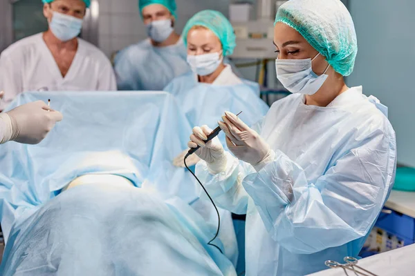 Équipe amicale de chirurgiens caucasiens en salle d'opération avec équipement chirurgical — Photo