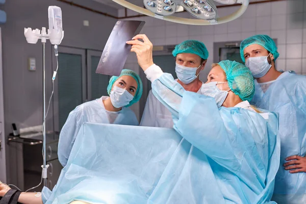 Trabalhadores médicos no hospital examinam impressões de raios X durante a operação — Fotografia de Stock