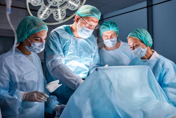 Équipe amicale de chirurgiens caucasiens en salle d'opération avec équipement chirurgical — Photo