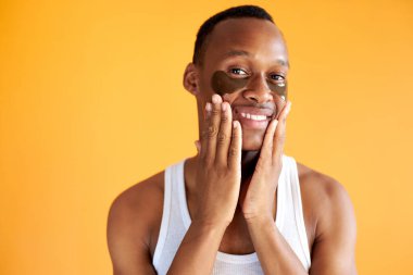 Sarı arka planda izole edilmiş kameraya gülümseyen Afro-Amerikan adam.