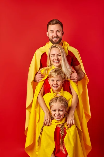 Vriendelijke Kaukasische familie op rij, het dragen van kostuums van superheld — Stockfoto