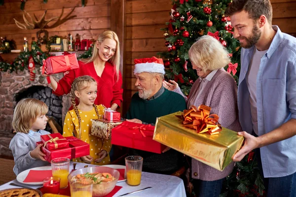 Счастливая кавказская семья дарит рождественские подарки своему милому дедушке — стоковое фото