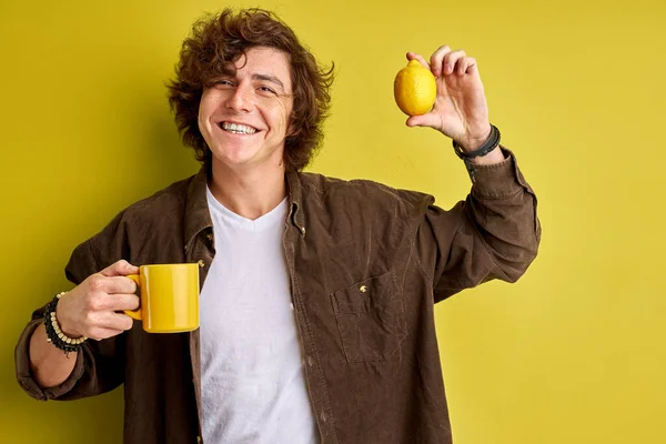 Dess kalla och emidemiska utanför glad attraktiv kille njuter av färsk aromatiskt te, isolerad på gul bakgrund — Stockfoto
