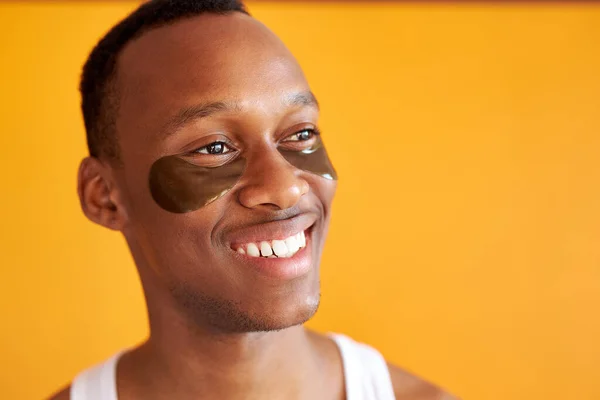 Retrato de homem americano africano sorridente com manchas de hidrogel preto sob os olhos — Fotografia de Stock