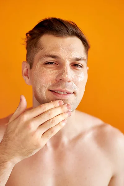 Homem caucasiano de boa aparência cuida de sua pele, hidrata — Fotografia de Stock