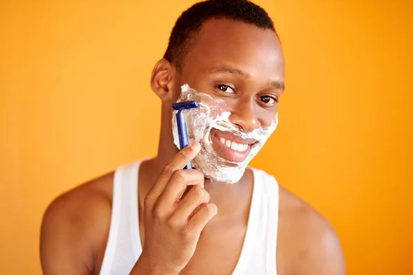 Afro américain sur fond jaune en mousse rasage avec un rasoir, portrait. — Photo