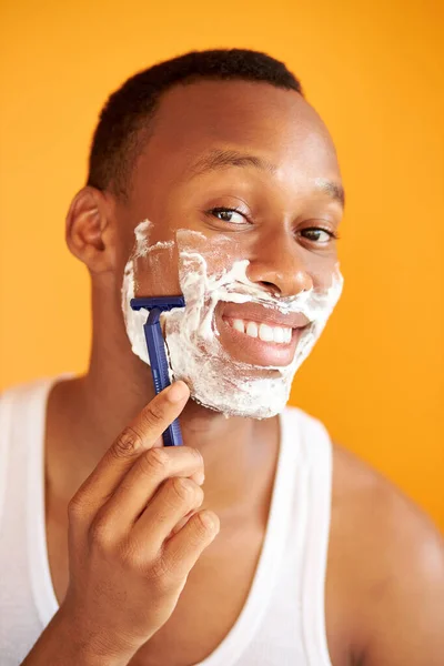 Noir afro homme rasage son visage avec la lame de rasoir à travers la mousse à raser — Photo