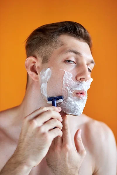 Hombre caucásico con espuma blanca en la cara, aislado sobre fondo naranja — Foto de Stock