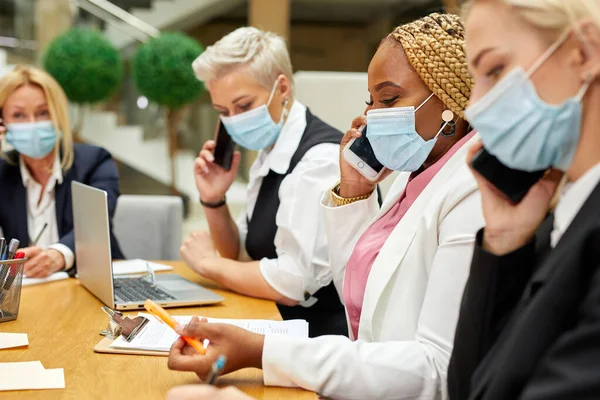 side view on business women talking on phone with partners in office