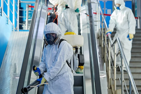 Equipo de valientes desinfectores esterilizando el edificio de escaleras mecánicas y centros comerciales — Foto de Stock