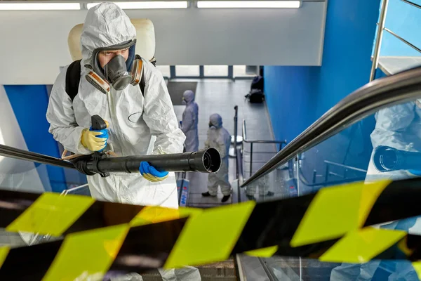 Ritratto di maschio disinfettante in tuta e maschera che lavora in territorio chiuso — Foto Stock